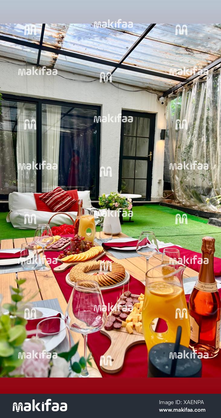 An arranged outdoor table with snacks, wine and juice 