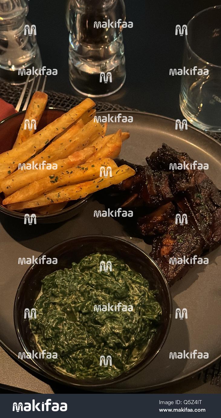 Un plateau de frites croustillantes, viande grillée et légumes verts