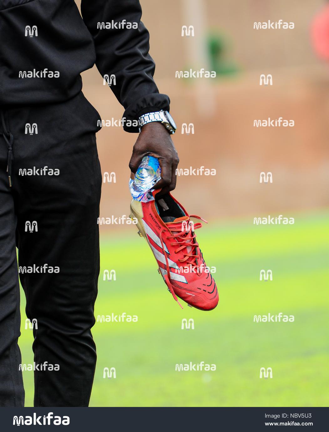 A pair of shoes held by a player on a soccer field