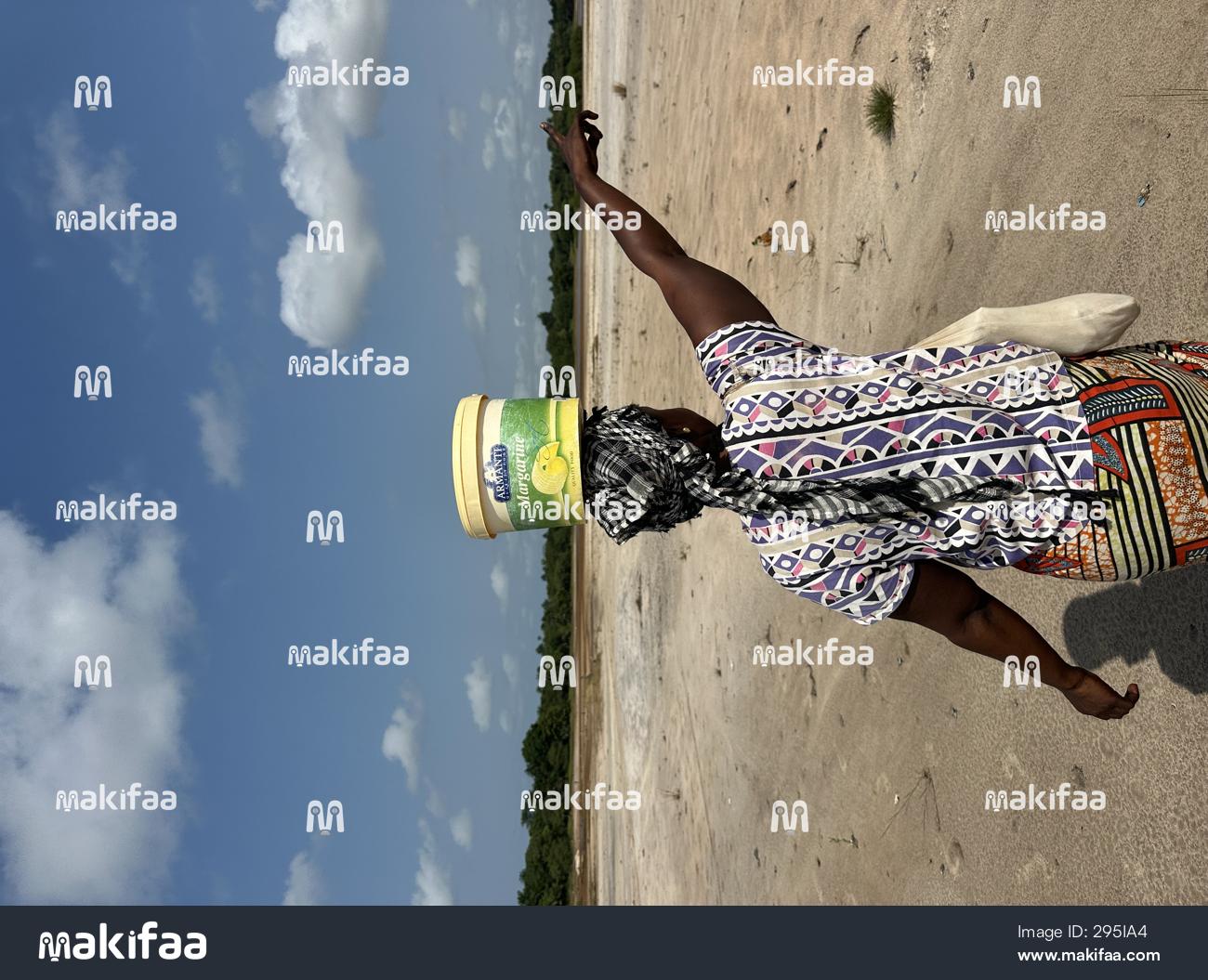 A woman walking with a bucket on her head