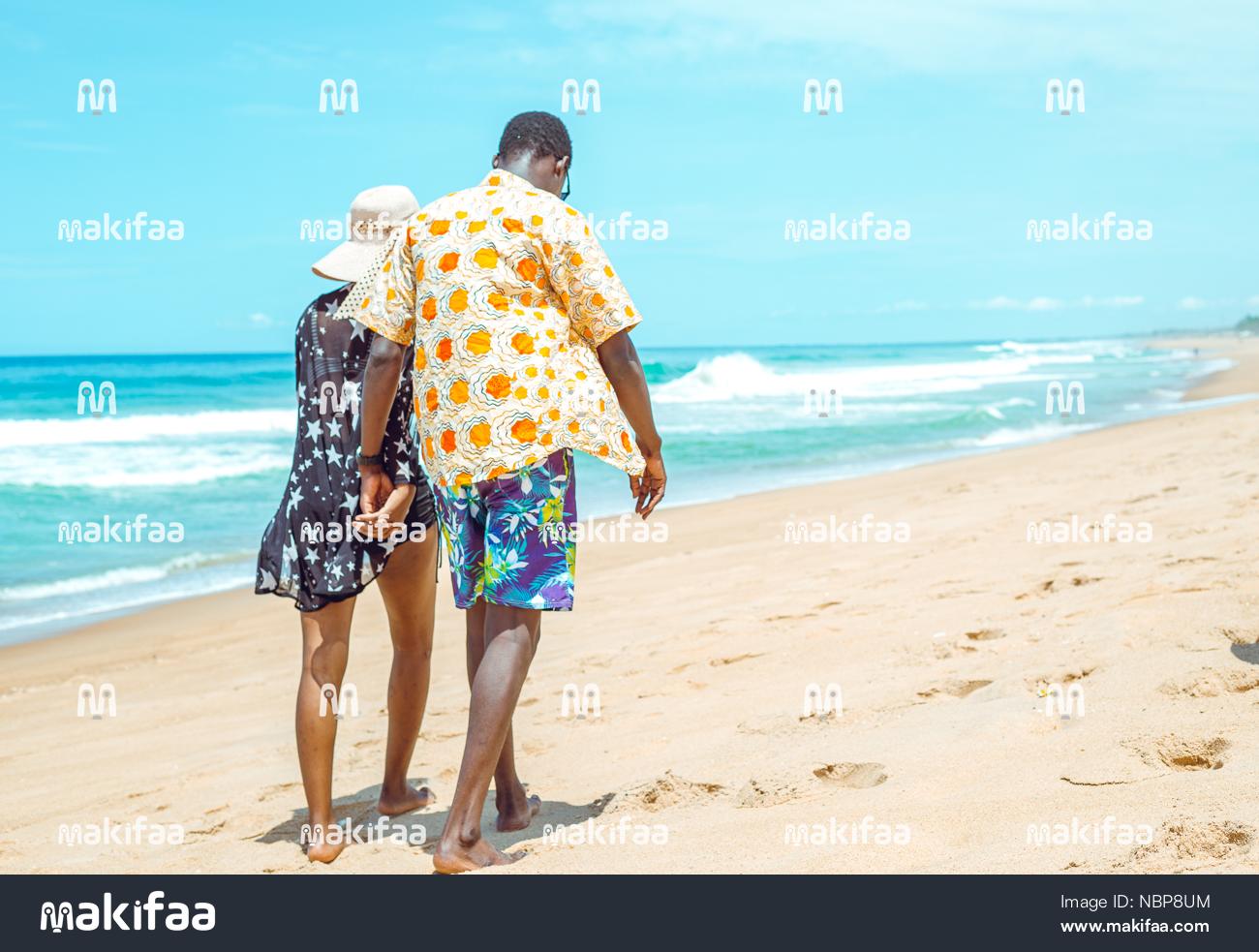 Mujer con sombrero caminando con su marido en la playa
