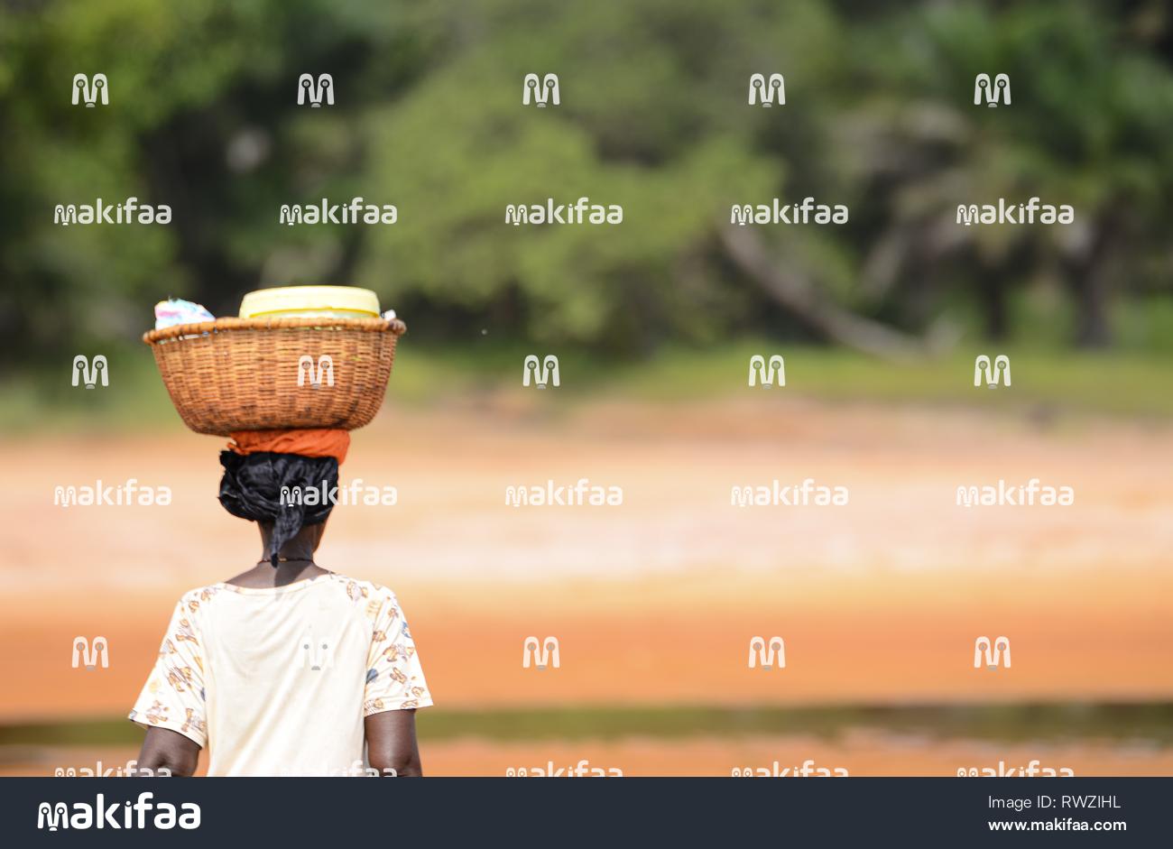 Uma mulher africana carregando uma cesta na estrada. 