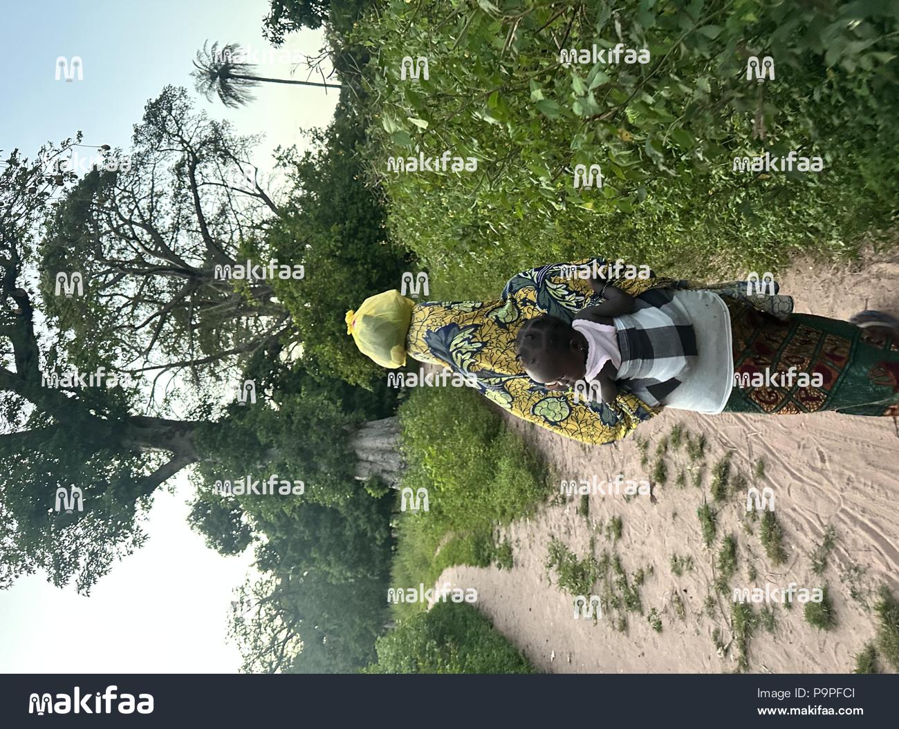 Woman walking in a field with her child on her back