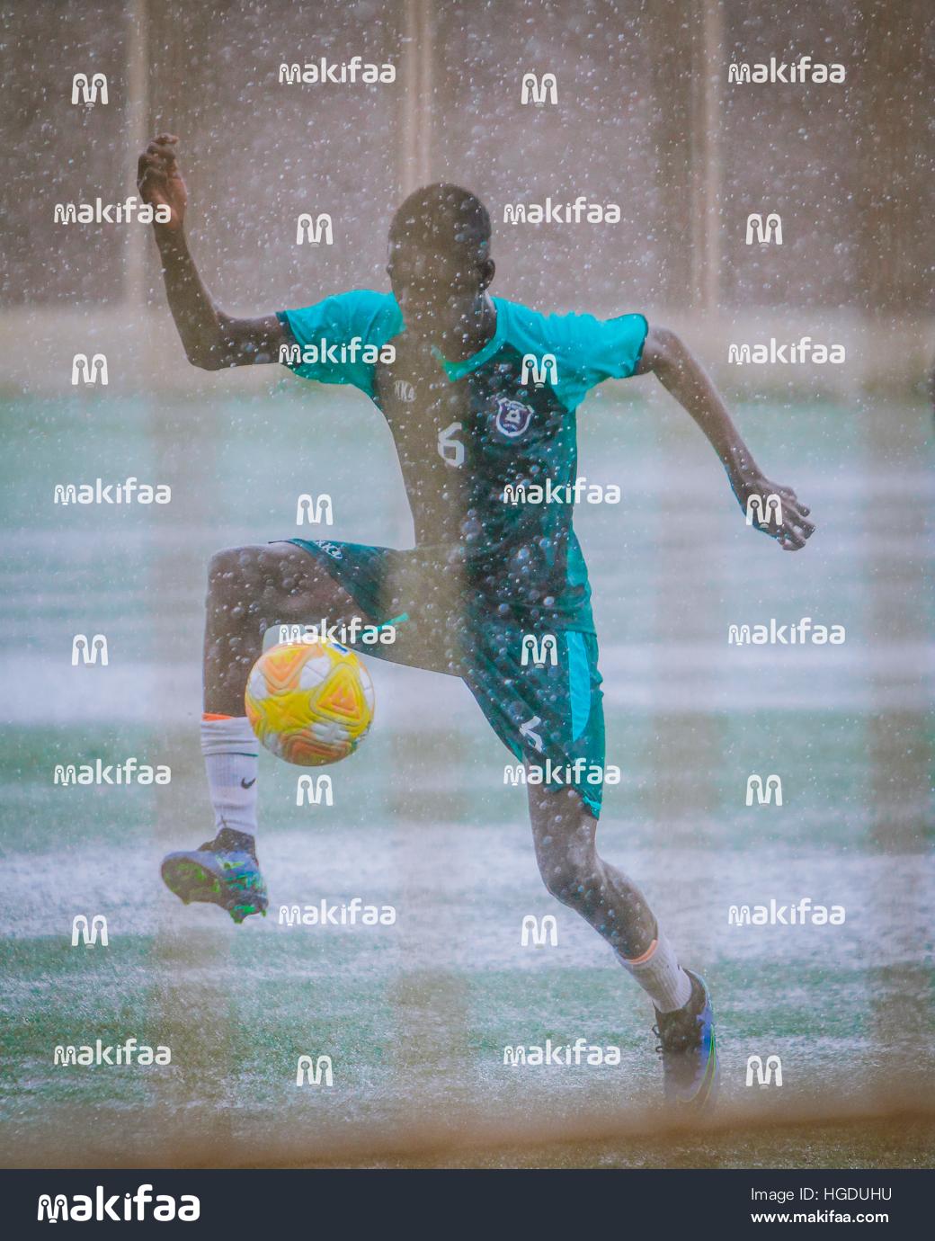 Joven jugando al fútbol bajo la lluvia 
