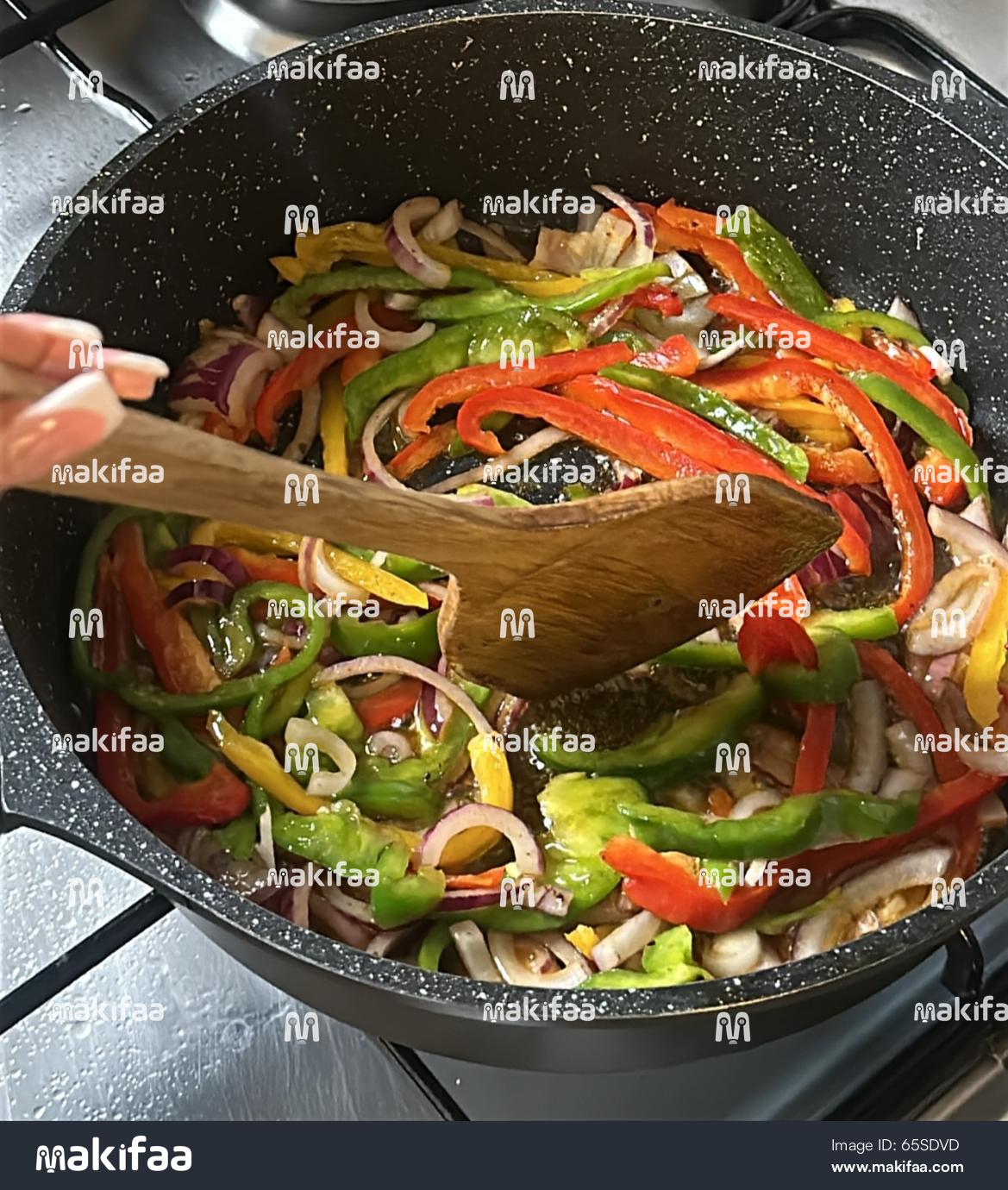 Fresh green and red peppers sizzle in hot cooking oil