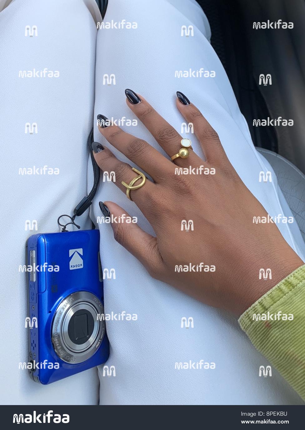 Hand with elegant rings beside a blue camera 