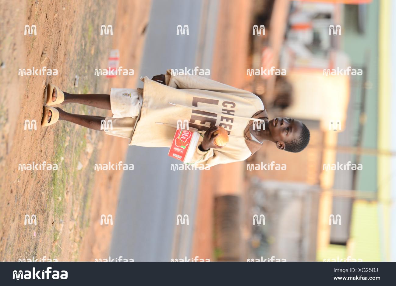 Enfant marchant sur la route avec un carton à la main