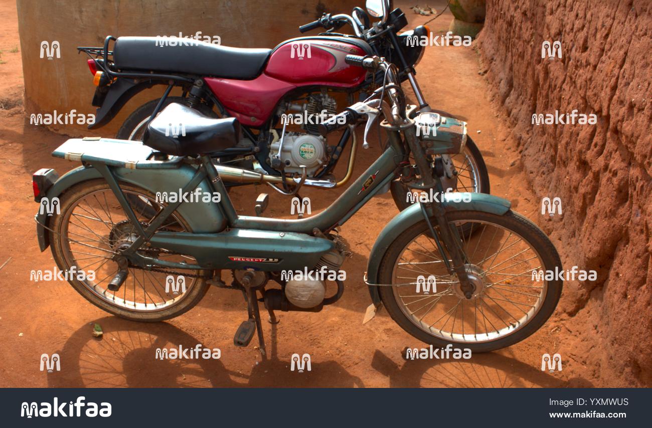 Moto Peugeot 103 vintage garée sur terre battue rouge, vue latérale détaillée