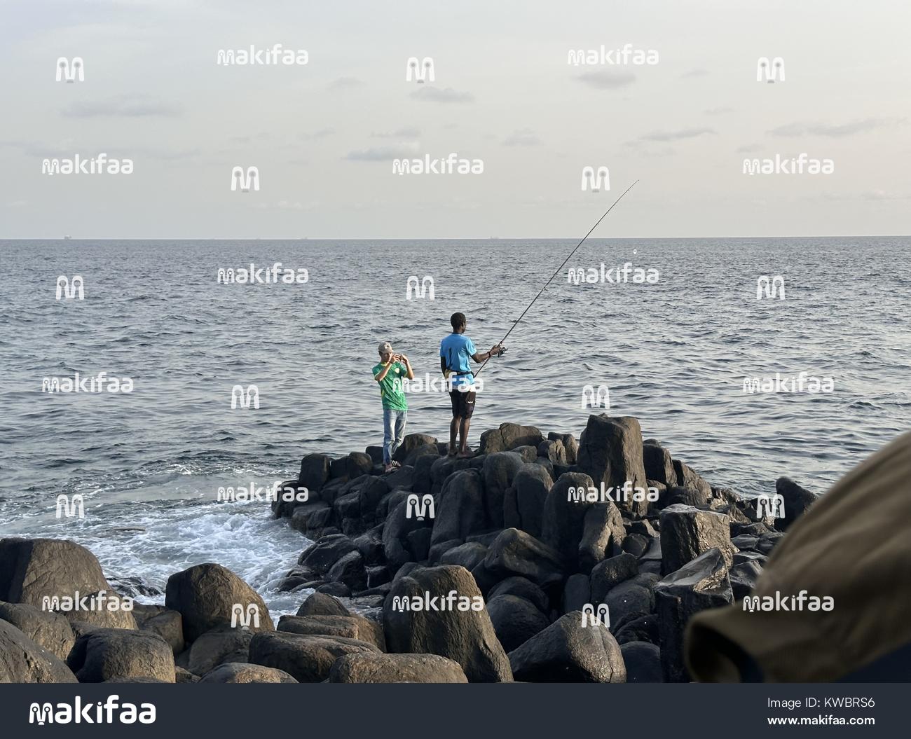 Dois homens pescando à beira-mar. 