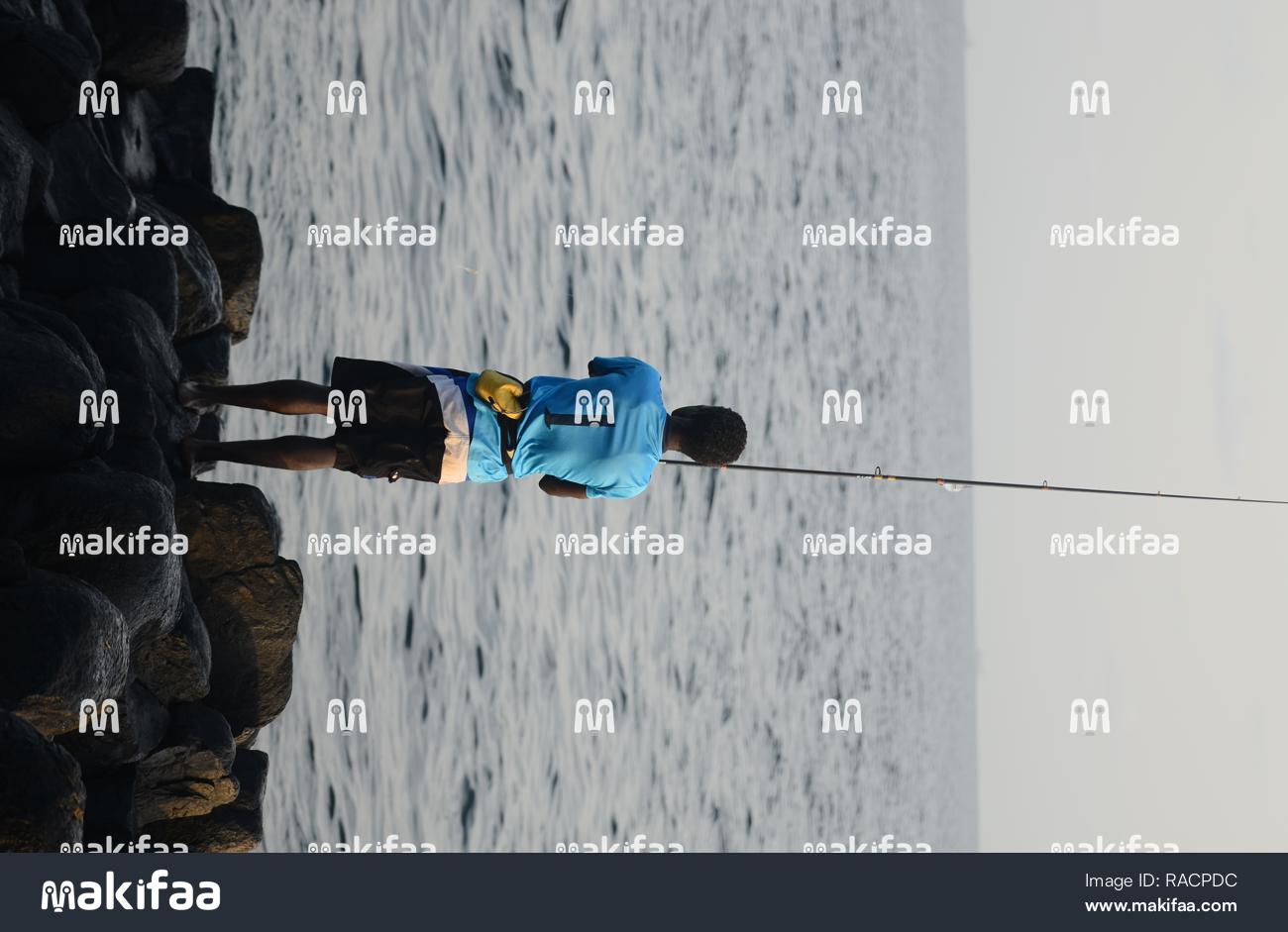 Um pescador trabalhando arduamente à beira-mar. 