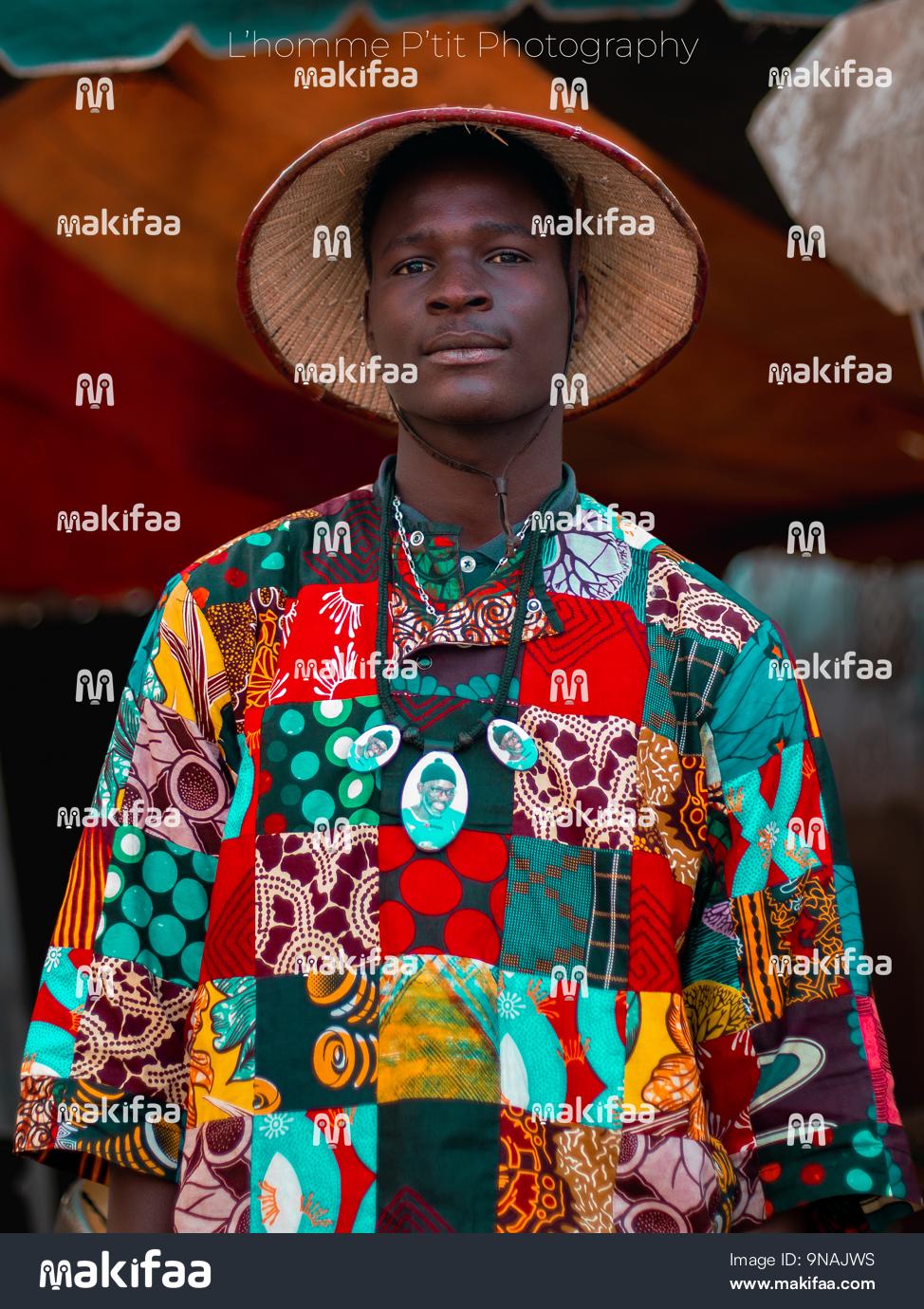 retrato de um jovem vestido com uma tanga multi-desenho e um chapéu com um olhar otimista