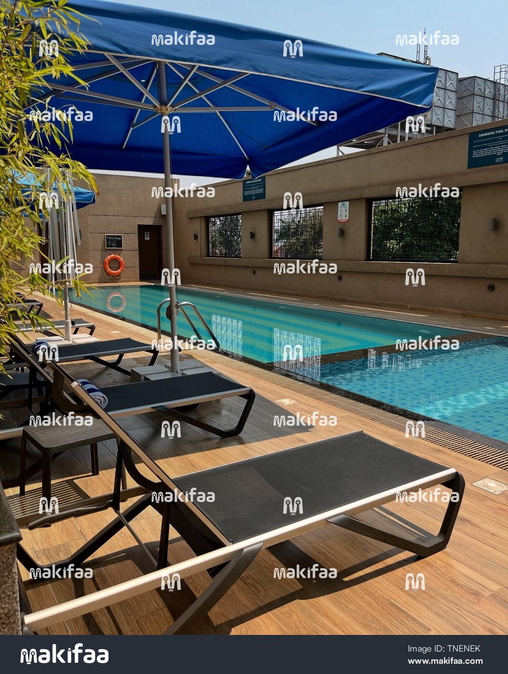 Piscina con terraza de madera y zona de relax amueblada.
