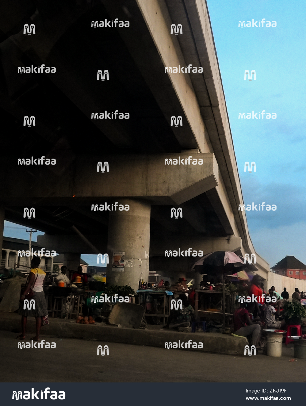 A bustling market under a city bridge 