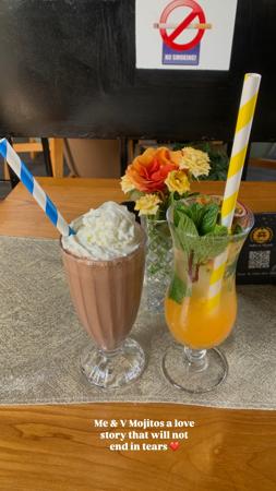Batido de chocolate y cóctel tropical servidos en la mesa de la cafetería.
