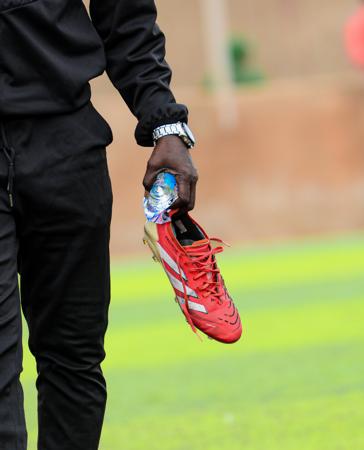 A pair of shoes held by a player on a soccer field