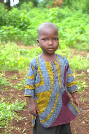 Retrato de uma criança africana em um boubou colorido, fundo de plantas