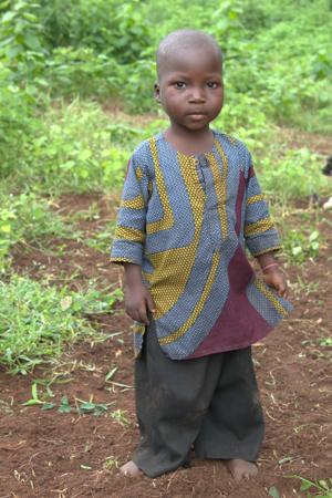 Criança africana em cera boubou colorida em um campo verde