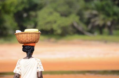 Uma mulher africana carregando uma cesta na estrada. 