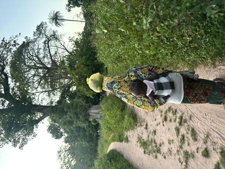 Woman walking in a field with her child on her back