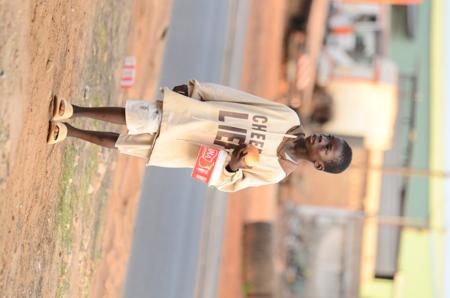 Enfant marchant sur la route avec un carton à la main