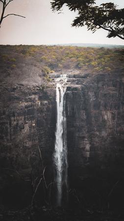 Waterfall cascading down a rocky cliff surrounded by forest