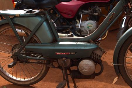 Motocicleta Peugeot 103 vintage estacionada em terra vermelha, vista lateral detalhada