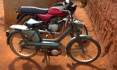 Motocicleta Peugeot 103 vintage estacionada em terra vermelha, vista lateral detalhada