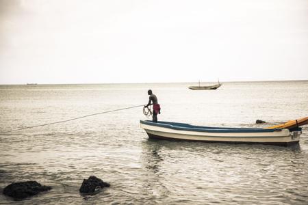 pescador no meio do mar em pé em uma canoa 