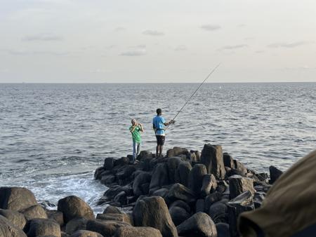 Dois homens pescando à beira-mar. 