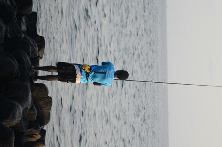 Um pescador trabalhando arduamente à beira-mar. 