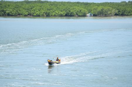Um homem em uma lancha atravessando um canal. 