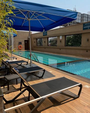 Piscina con terraza de madera y zona de relax amueblada.