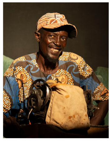 Un homme souriant devant sa machine à coudre