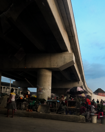 A bustling market under a city bridge